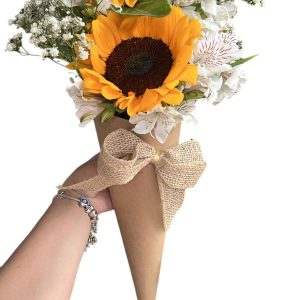 Cone de papel kraft com girassol, flores brancas e laço de juta.